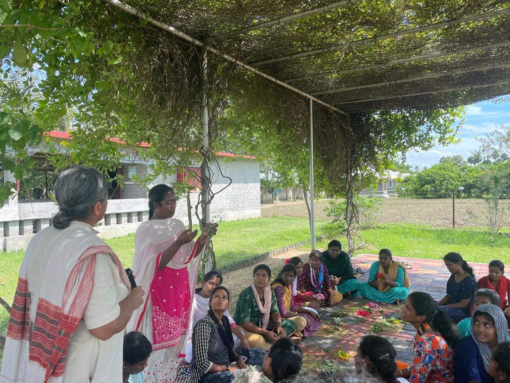 Farmer ploughing a field using a traditional wooden plough pulled by a pair of white oxen, surrounded by greenery and large trees at Sreyes Farm.